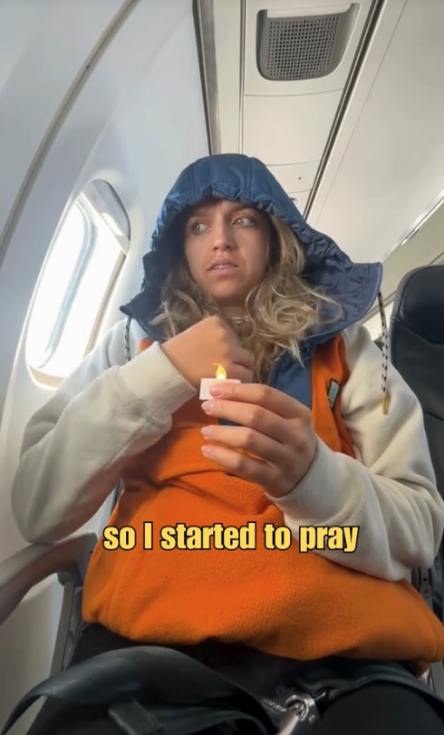 A woman sits on a plane, holding a candle as part of a Colombian tradition on December 7